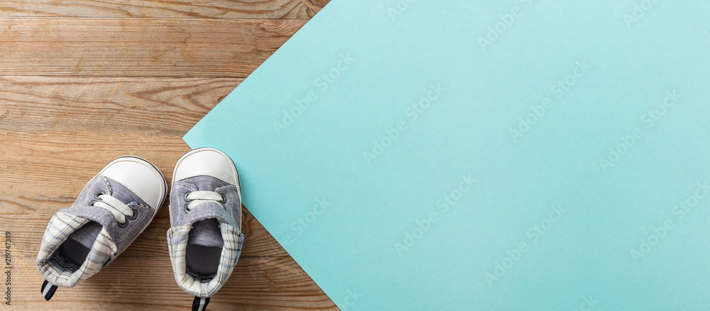 Baby boy shoes on pastel blue and wooden background, banner - obrazy, fototapety, plakaty 