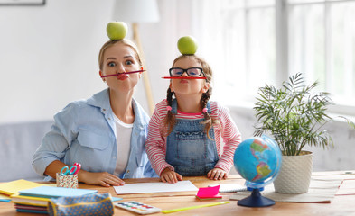 funny mother and child daughter doing homework writing and reading