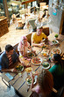 © pressmaster - Five young friends sitting by large served wooden table and enjoying food and talk in cafe or restaurant