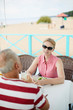 © pressmaster - Restful senior woman in sunglasses and mature man in front having talk while relaxing by table