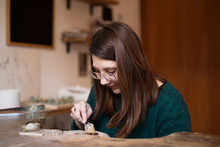 Woman Carving At Worktable With Instrument