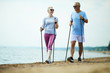 © pressmaster - Happy active aged couple trekking along coastline on sandy beach in the morning