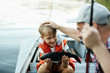 © pressmaster - Happy boy holding big fish, and showing it to his father, while they are on the boat