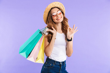 Canvas Print - Happy cute woman showing okay gesture holding shopping bags.