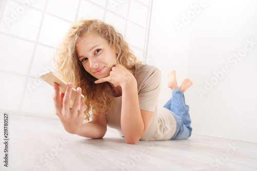 Fotografie, Obraz lying young woman on floor talking on cellphone, with long hair dressed in jeans