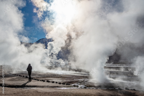 Fotomural El Tatio geysers in Chile, Silhouette of a woman walking among the steams and fu