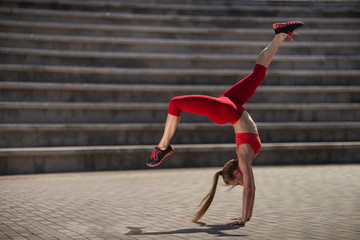 Young attractive woman practicing yoga outdoors. The girl performs a handstand upside down