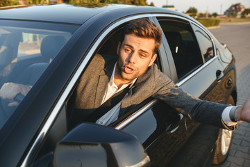 Close-up of an angry man looking outside car window