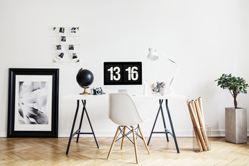 Canvas Print - Poster and plant in white workspace interior with chair at desk with desktop computer. Real photo