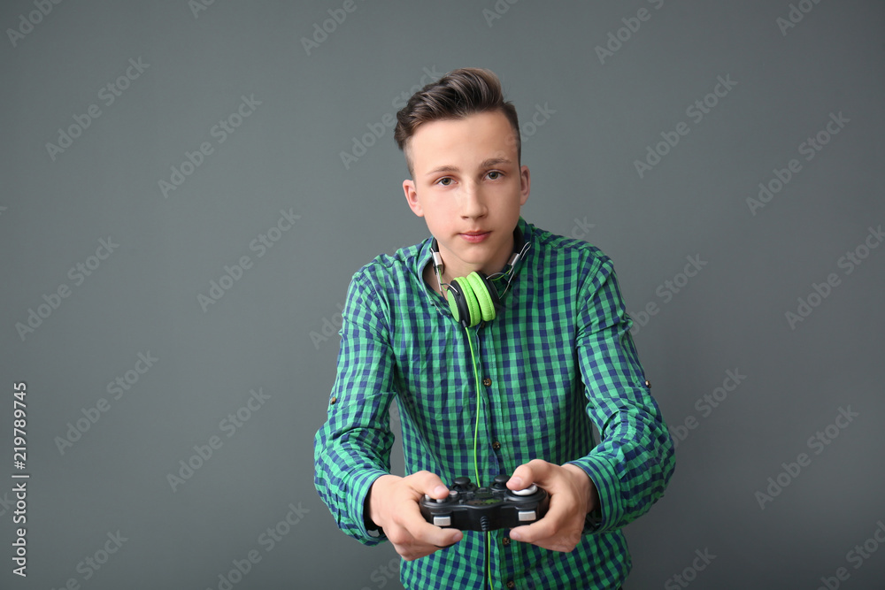 Teenager with gamepad on grey background