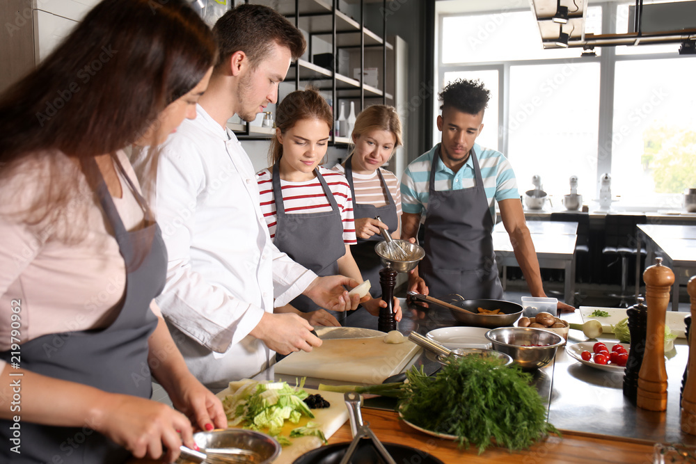 Chef and group of young people during cooking classes - obrazy, fototapety, plakaty 