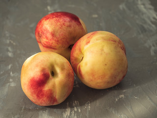 Three large ripe nectarines on a wooden background