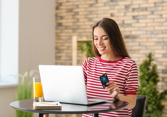 Young woman shopping online with credit card and laptop in cafe