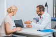 © LIGHTFIELD STUDIOS - physiotherapist in white coat having conversation with female patient at workplace with laptop in hospital