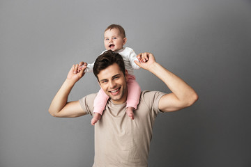 Image of happy father man carrying his little child on neck, isolated over gray background