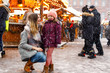 Little cute kid girl and young mother having fun on traditional German Christmas market during strong snowfall. Happy child and beautiful woman enjoying family market in Germany, Dresden