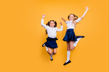 Poster - Dynamic images. Motion, movement, action concept. Full length, legs, body, size portrait of carefree, careless, adorable, beautiful, small girls jumping isolated on yellow background