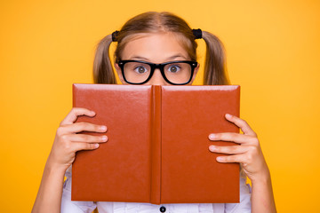 Sticker - Half faced close up studio photo portrait of beautiful small little lovely clever shocked surprised glad frightened schoolkid closing face with book hold in hands isolated background