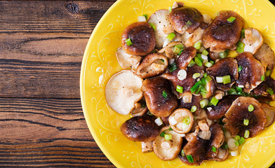 Fried mushrooms shiitake with green onion on wooden background. Chinese food.Top view. Flat lay