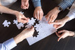 © fizkes - Top close up view of diverse employees assembling jigsaw puzzle trying to find best business solution, workers engaged in teambuilding practicing unity and support. Concept of successful cooperation