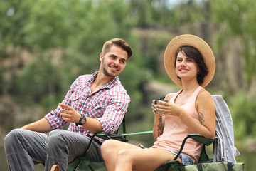 Poster - Young couple resting near forest, outdoors. Camping season