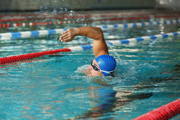 Young athletic man swimming in pool indoors