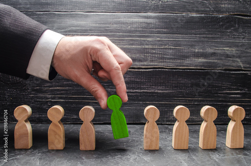 Fotografiet hand of a businessman takes a wooden figure of a man