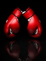 A pair of red boxing gloves,l on reflective surface