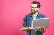 © denis_vermenko - Confident business expert. Confident young handsome man in shirt holding laptop and smiling while standing against pink background