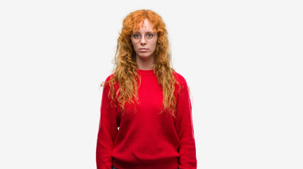 Poster - Young redhead woman wearing red sweater with serious expression on face. Simple and natural looking at the camera.