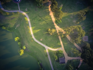 Wall Mural - Vintage tone aerial urban lakeside green park in suburban area Houston. Trees, grassy lawn, playground, pathway, trail by lake shore for jogging, running, people exercising outdoor