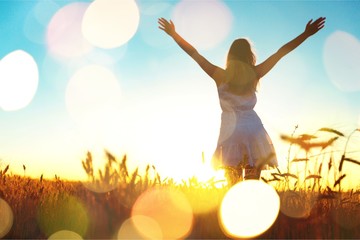 Young woman on field under sunset light