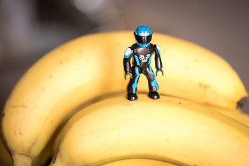 Plastic figurine standing and climbing bananas with a blurred background ideal for healthy diet to promote cleanse and healthy life and exercises or weight control