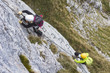 © Ondra - Woman and group of other people climbing on steep rock face on via ferrata. Climbers on via ferrata climbing route. Alpine ferrata ascent to summit. Summer adventure mountain activity.