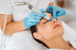 Cleansing procedure. Nice pretty woman lying with her eyes closed while having a cleansing procedure on her face
