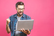 © denis_vermenko - I'm a winner! Happy man holding laptop and celebrating his success over pink background.