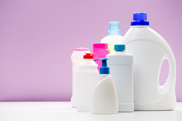 Wall Mural - Photo of bottles of cleaning products on white table isolated on purple background