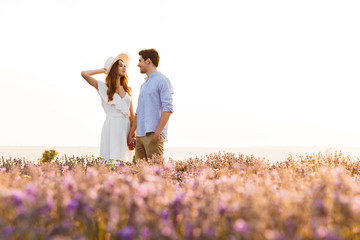 Wall Mural - Photo of beautiful young people dating, and walking together outdoor in lavender field