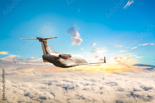 Fotografie, Obraz Jet plane flying high up over clouds into sunset