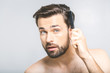 © denis_vermenko - Portrait of handsome young man combing his hair in bathroom. Isolated over grey background.