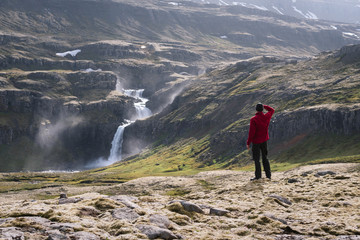 Wall Mural - Tourist looks at a waterfall in Iceland