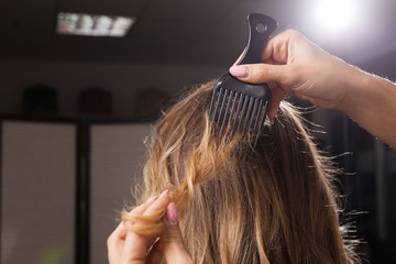 Wall Mural - close up photo of professional hairdresser brushing hair of a model with waving coiffure in a beauty salon at a master class. concept of stylist training