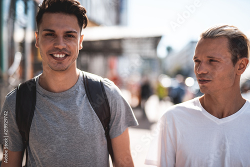 Portrait Of Beaming Male Telling With Orderly Man While Going At