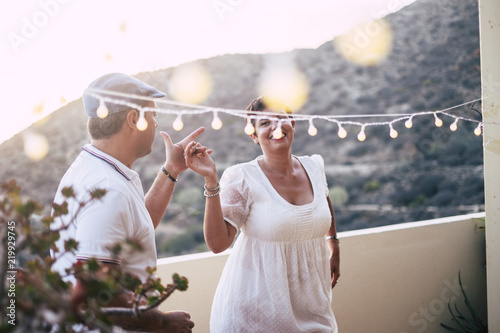 Fotografia happy caucasian people dancing together at home in terrace with lights during the sunset