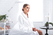 © Yakobchuk Olena - Feeling relaxed. Pretty girl waiting for cosmetologist. She is wearing soft white bathrobe and looking away with calmness