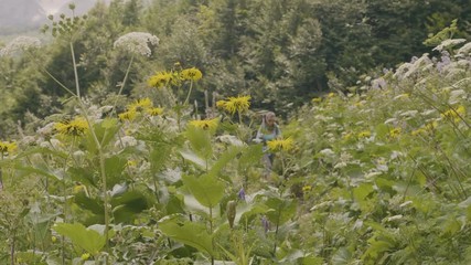 Wall Mural - traveling woman with tourist backpack walking on summer meadow while hiking