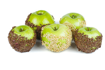 Wall Mural - Hand dipped caramel green apples covered with flax and sesame seeds isolated on white background