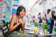 A portrait of an attractive beautiful Chinese Asian millennial teenager girl sitting and chilling at a cafe along a crowded street during the day.