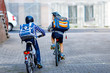 © Irina Schmidt - Two school kid boys in safety helmet riding with bike in the city with backpacks. Happy children in colorful clothes biking on bicycles on way to school. Safe way for kids outdoors to school