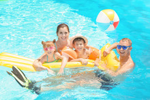 Happy Family With Inflatable Mattress In Swimming Pool